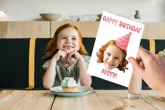 Custom birthday card with child’s face and party hat, personalised with name “Abby” in pink. Fun, unique keepsake gift for kids’ birthdays.