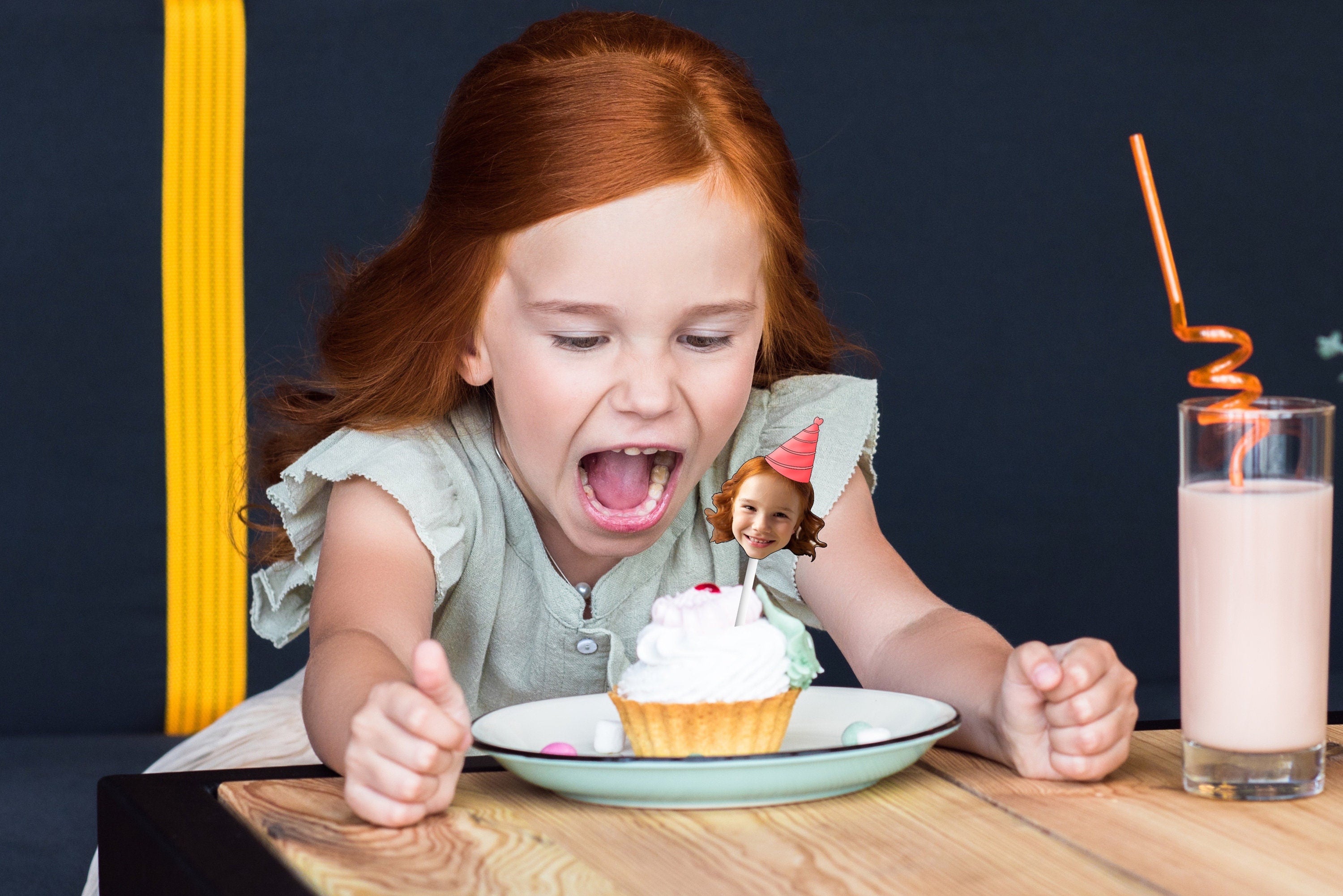 A festive decoration featuring a cut-out of a person&#39;s head wearing a colorful party hat, placed on top of a delicious cupcake, perfect for a birthday celebration.