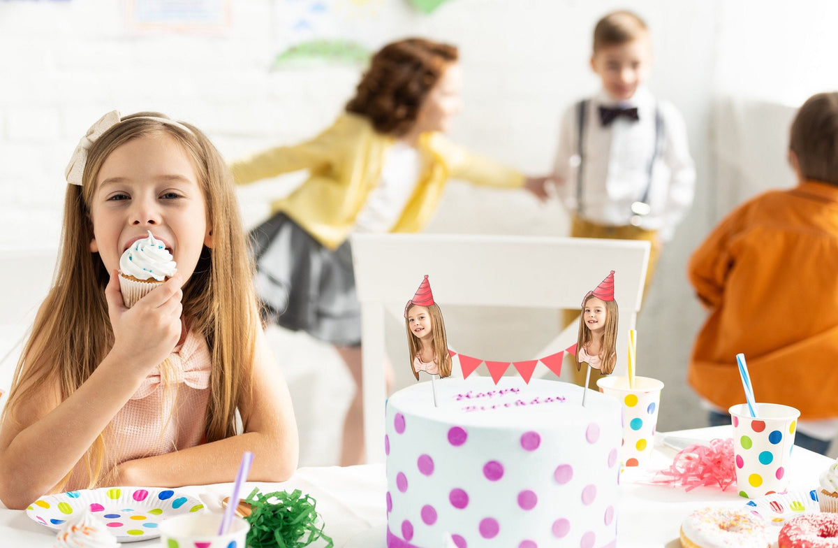 Kids’ birthday cake with custom face bunting topper and party hat design, surrounded by cupcakes, colourful tableware, and polka dot decorations. Perfect personalised party decoration.