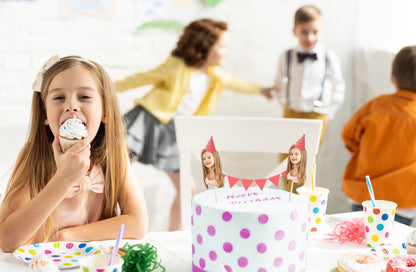Kids’ birthday cake with custom face bunting topper and party hat design, surrounded by cupcakes, colourful tableware, and polka dot decorations. Perfect personalised party decoration.