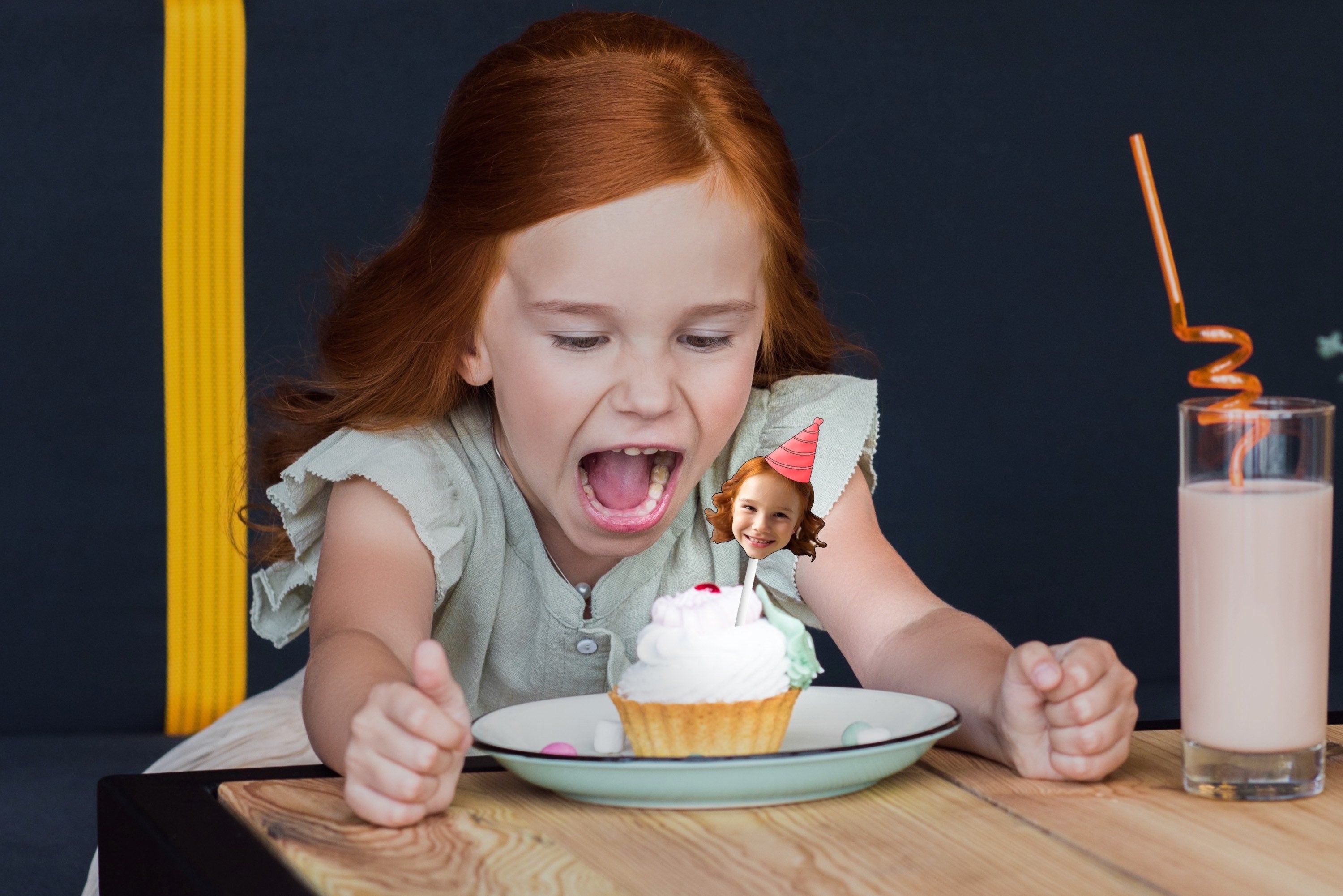 A festive decoration featuring a cut-out of a person&#39;s head wearing a colorful party hat, placed on top of a delicious cupcake, perfect for a birthday celebration.